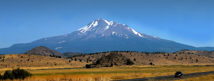 a truck driving down a road in front of a mountain