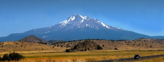 a truck driving down a road in front of a mountain
