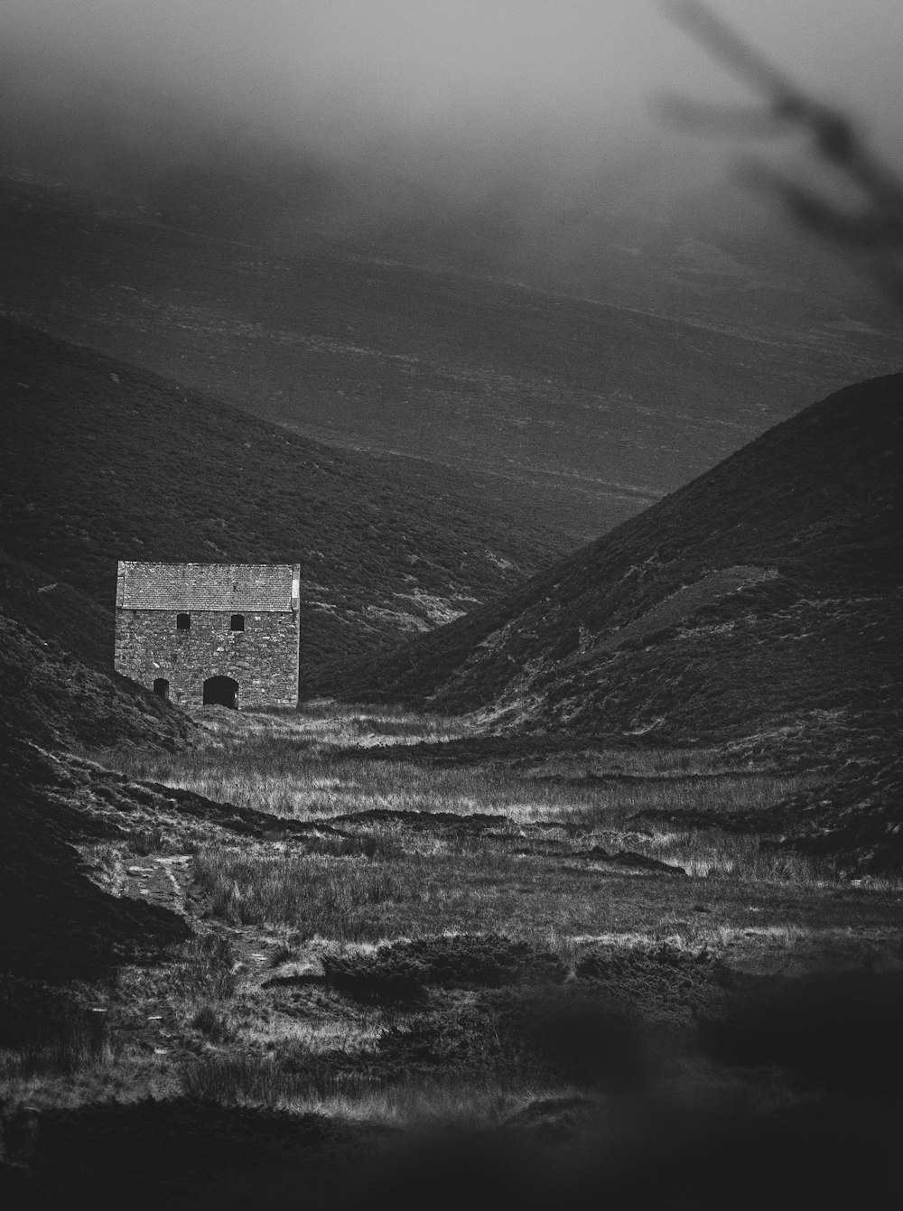 a black and white photo of a house in the mountains