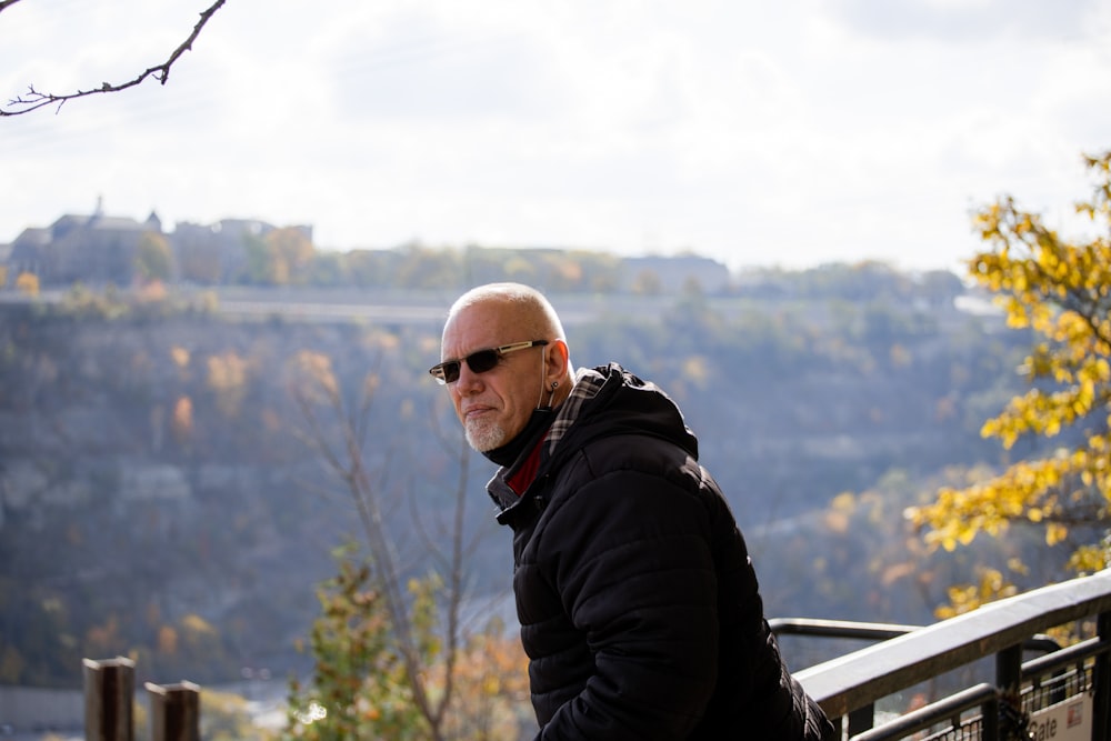 a bald man wearing sunglasses sitting on a bench