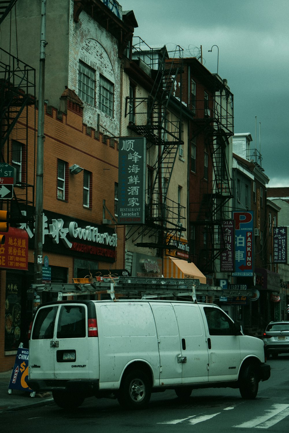 a white truck driving down a street next to tall buildings