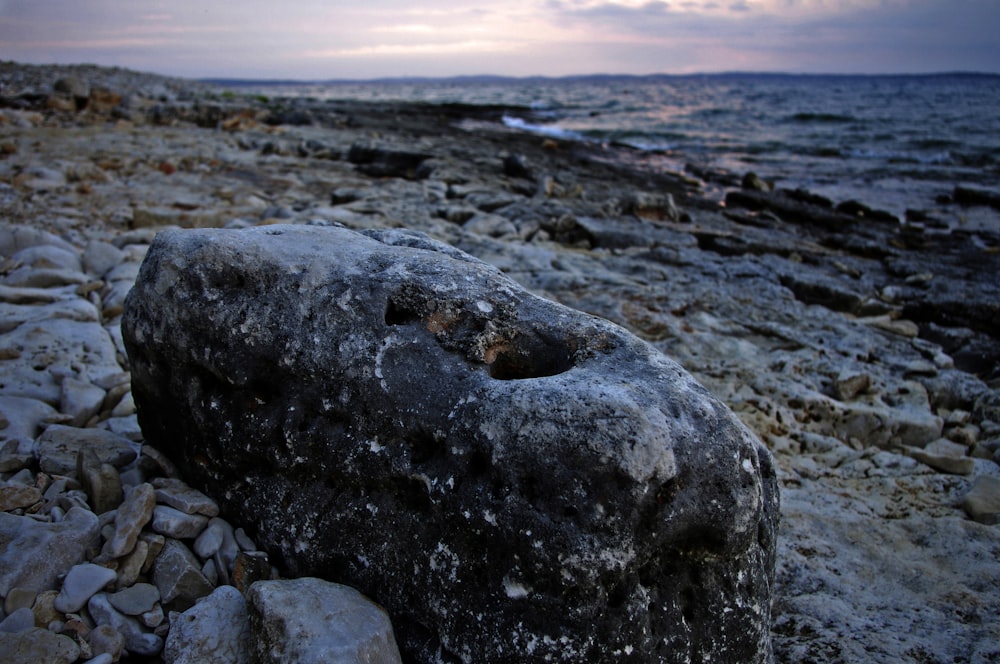 un gros rocher assis au sommet d’une plage rocheuse