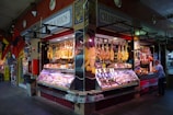 a man standing in front of a store filled with meat