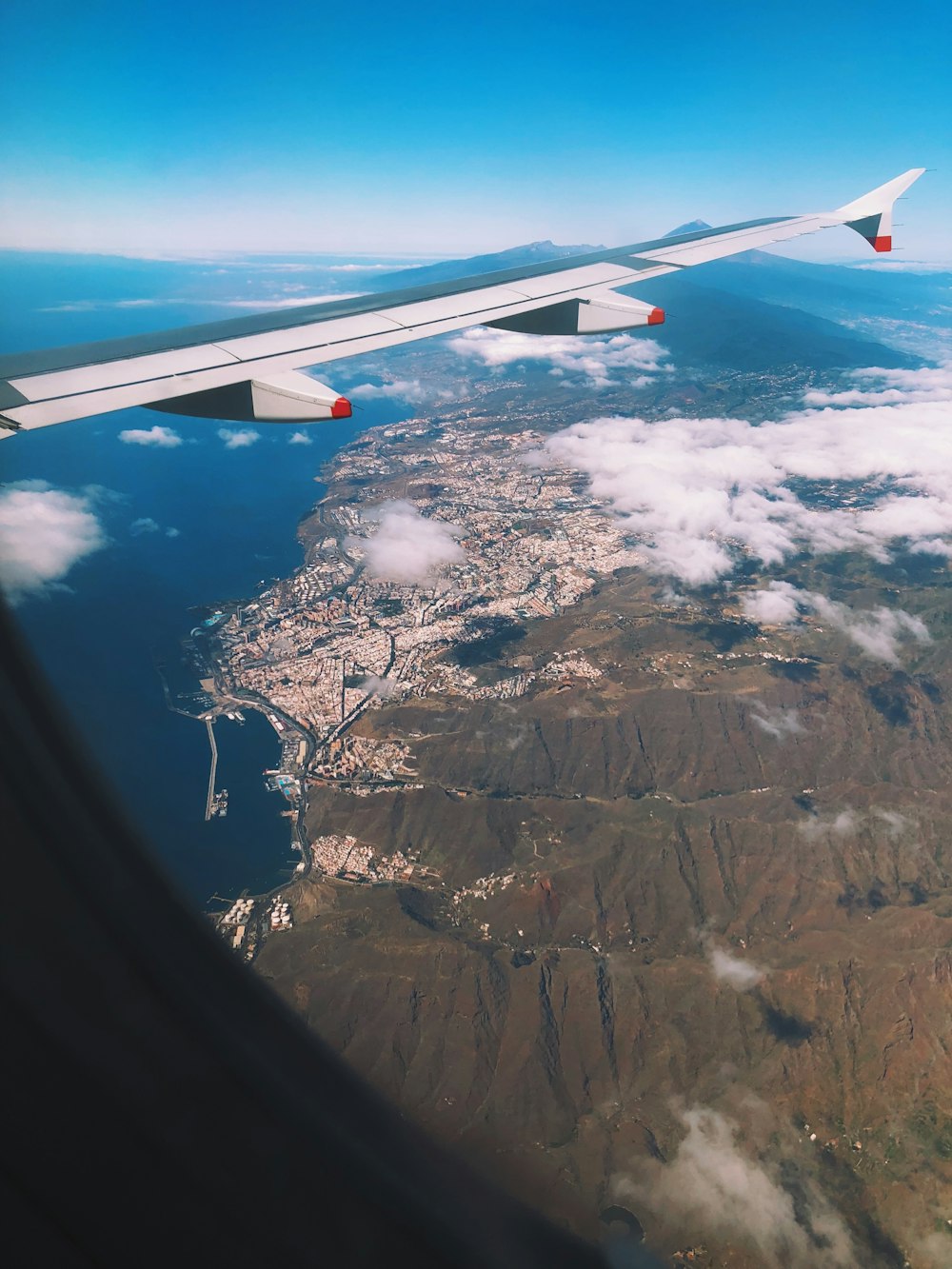 a view of the wing of an airplane flying over a city