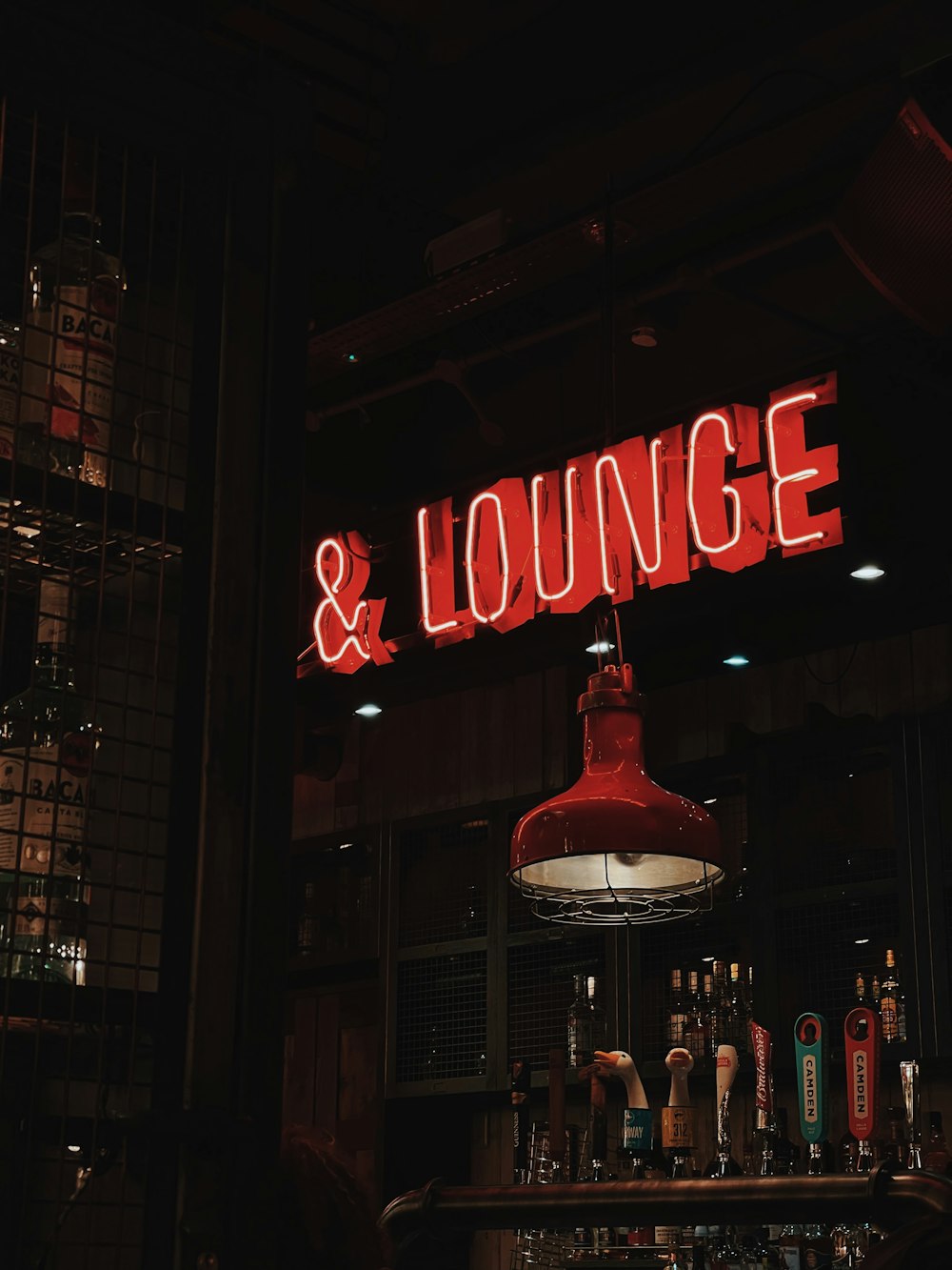 a neon sign that reads & lounge above a bar