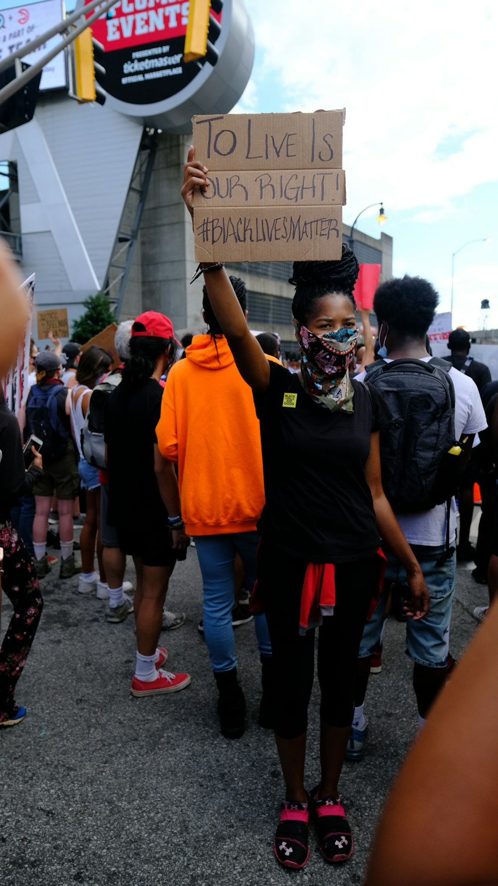 a woman holding a sign in the middle of a crowd