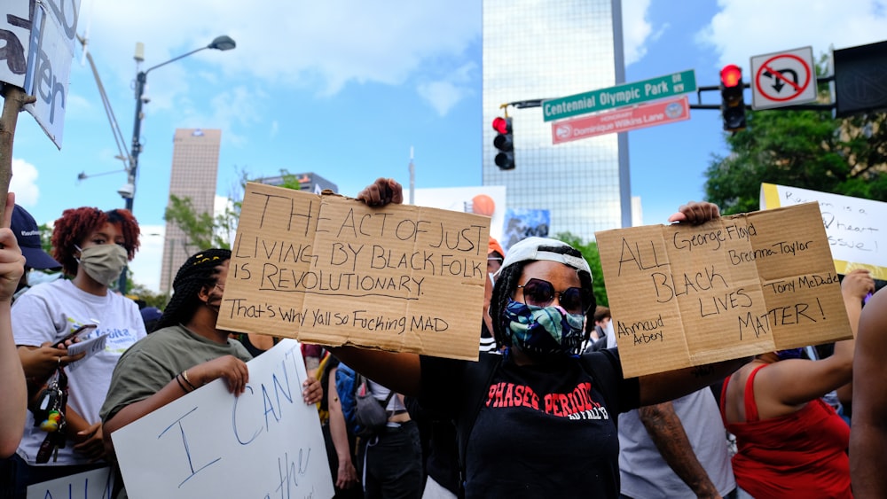 a group of people holding signs and wearing masks