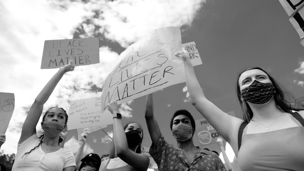 a group of people holding signs and wearing masks