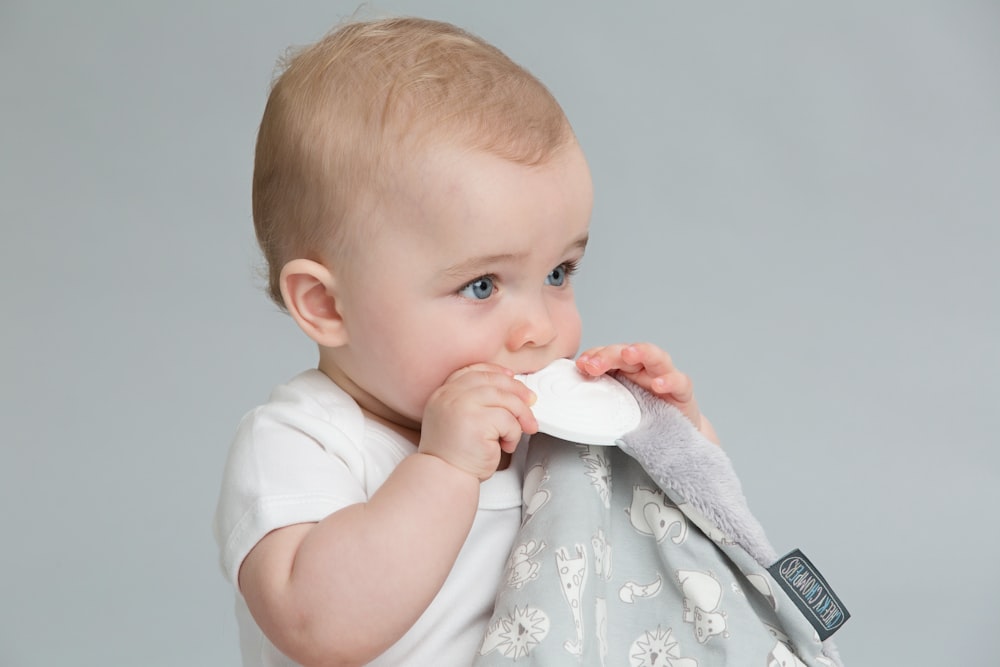 a baby is holding a napkin in his mouth