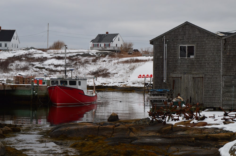 a red boat sitting in the water next to a house