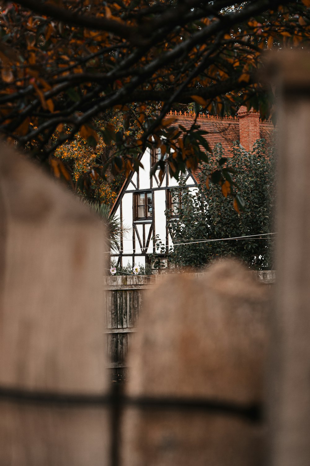 a house through a fence with a clock tower in the background