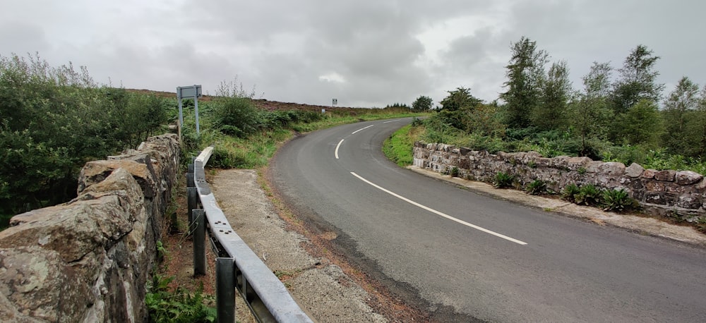 a curved road with a stone wall next to it