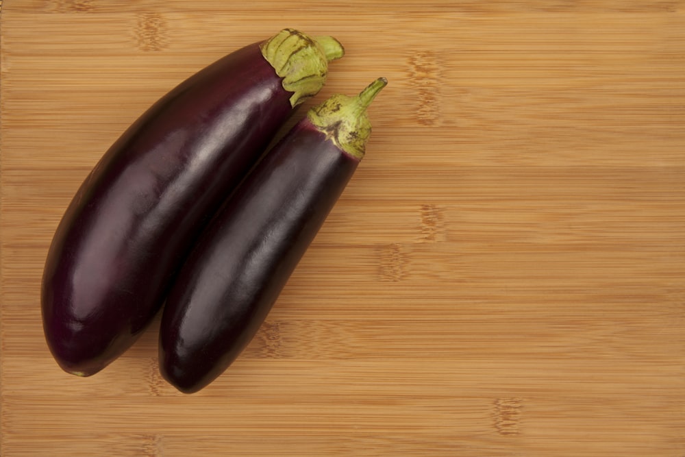 two eggplant on a wooden cutting board