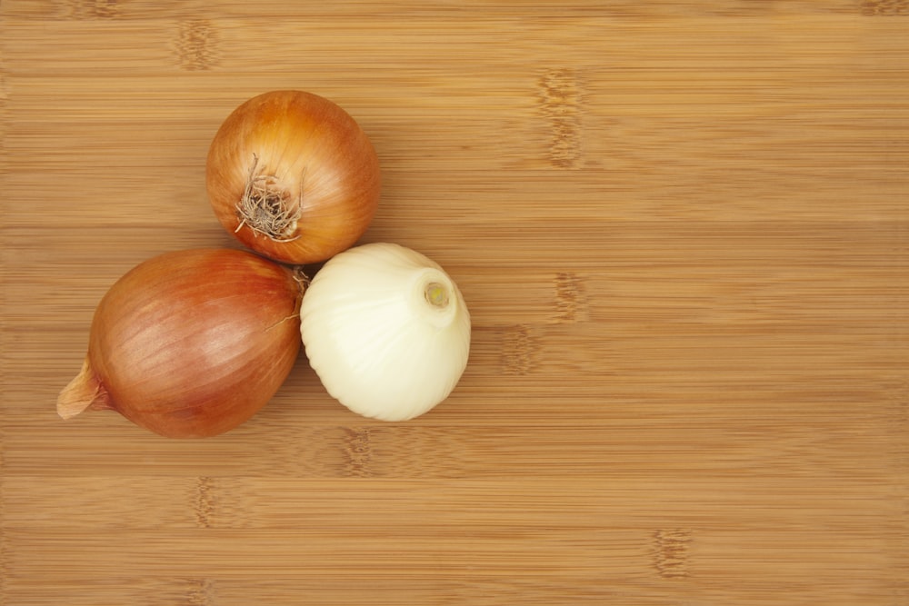 a couple of onions sitting on top of a wooden cutting board