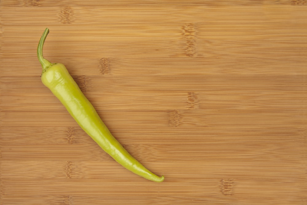 a green pepper sitting on top of a wooden cutting board