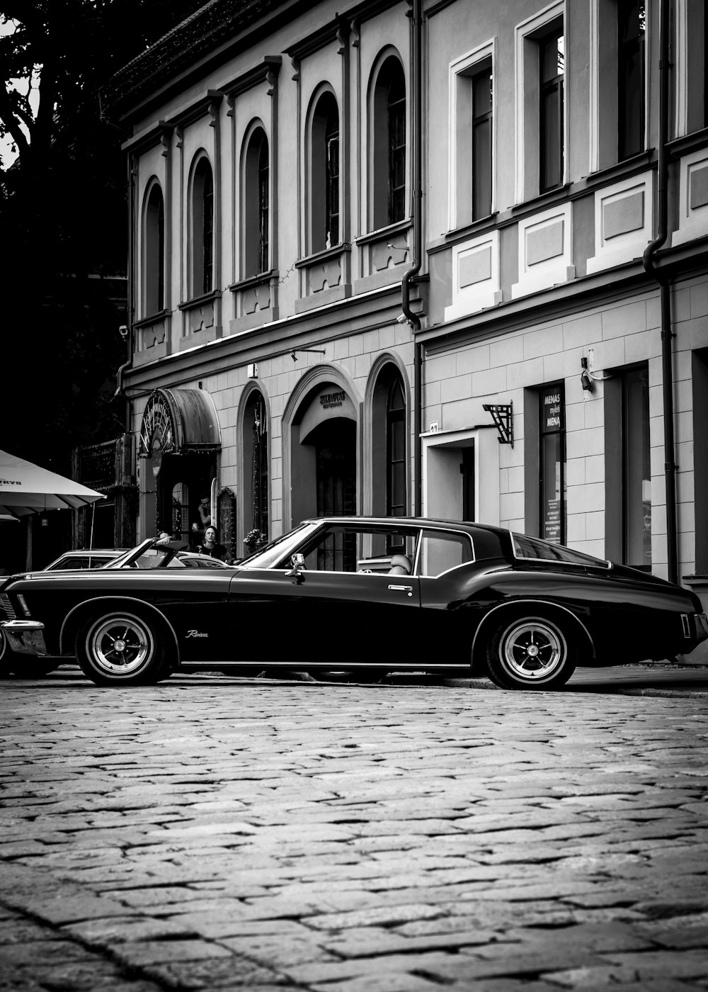 a black and white photo of a car parked in front of a building