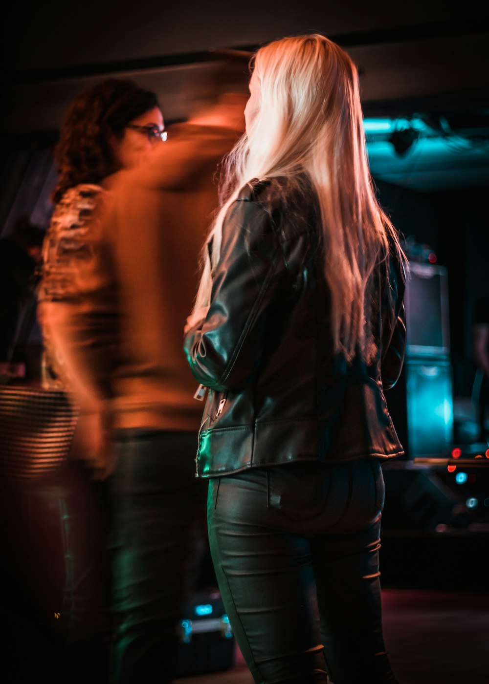 a woman in a leather jacket standing in front of a group of people