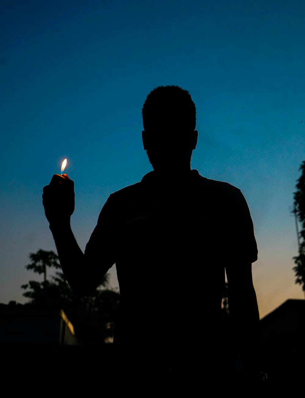 a silhouette of a man holding a lit candle