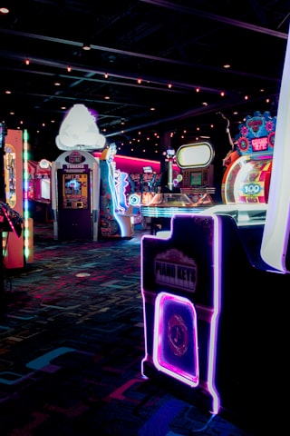 A room filled with retro arcade machines under deep neon light
