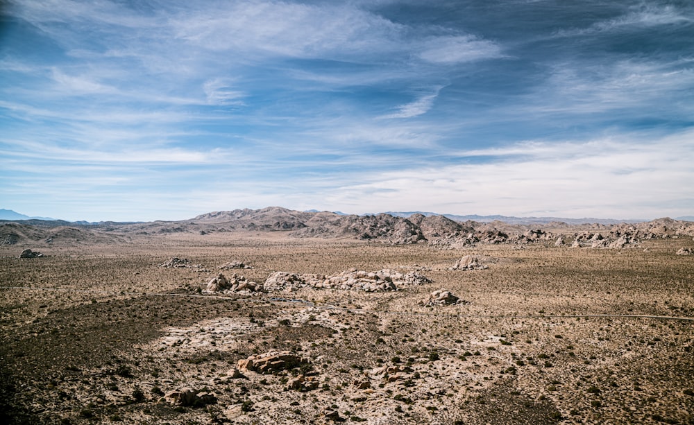 a view of a desert with rocks and mountains in the background