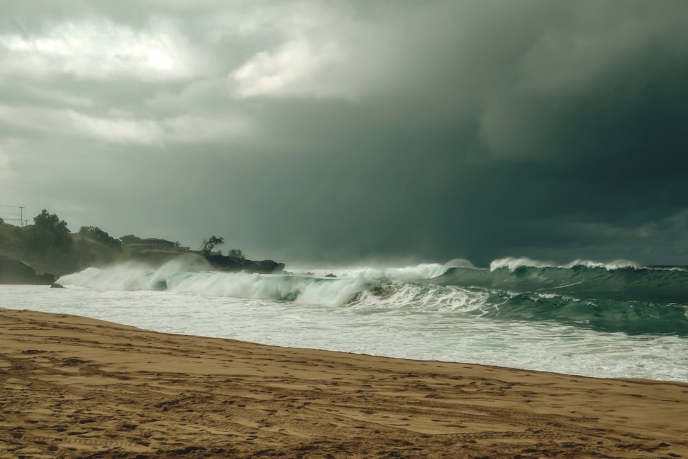 a sandy beach with waves crashing on the shore