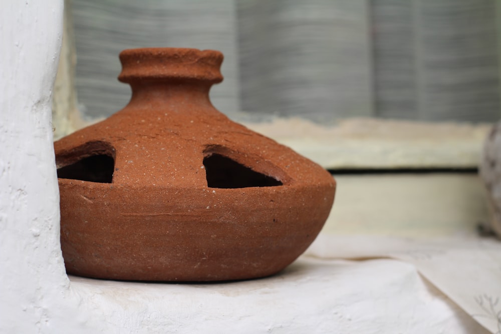 a brown vase sitting on top of a white table