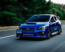 a blue subarunt is driving down the road