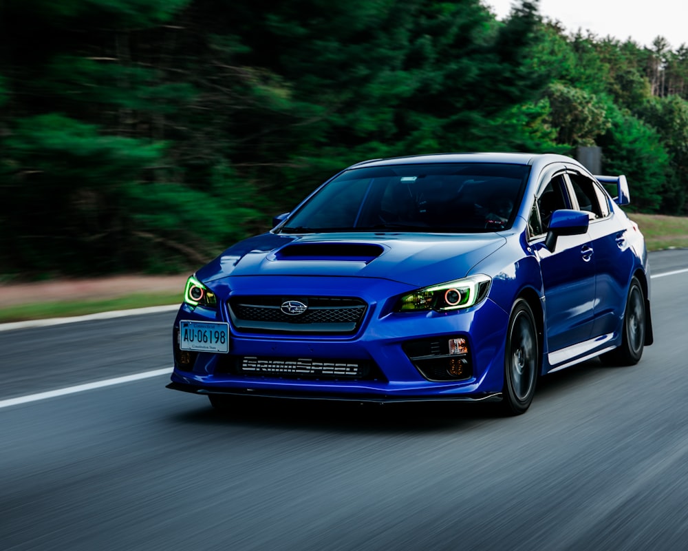 a blue subarunt is driving down the road