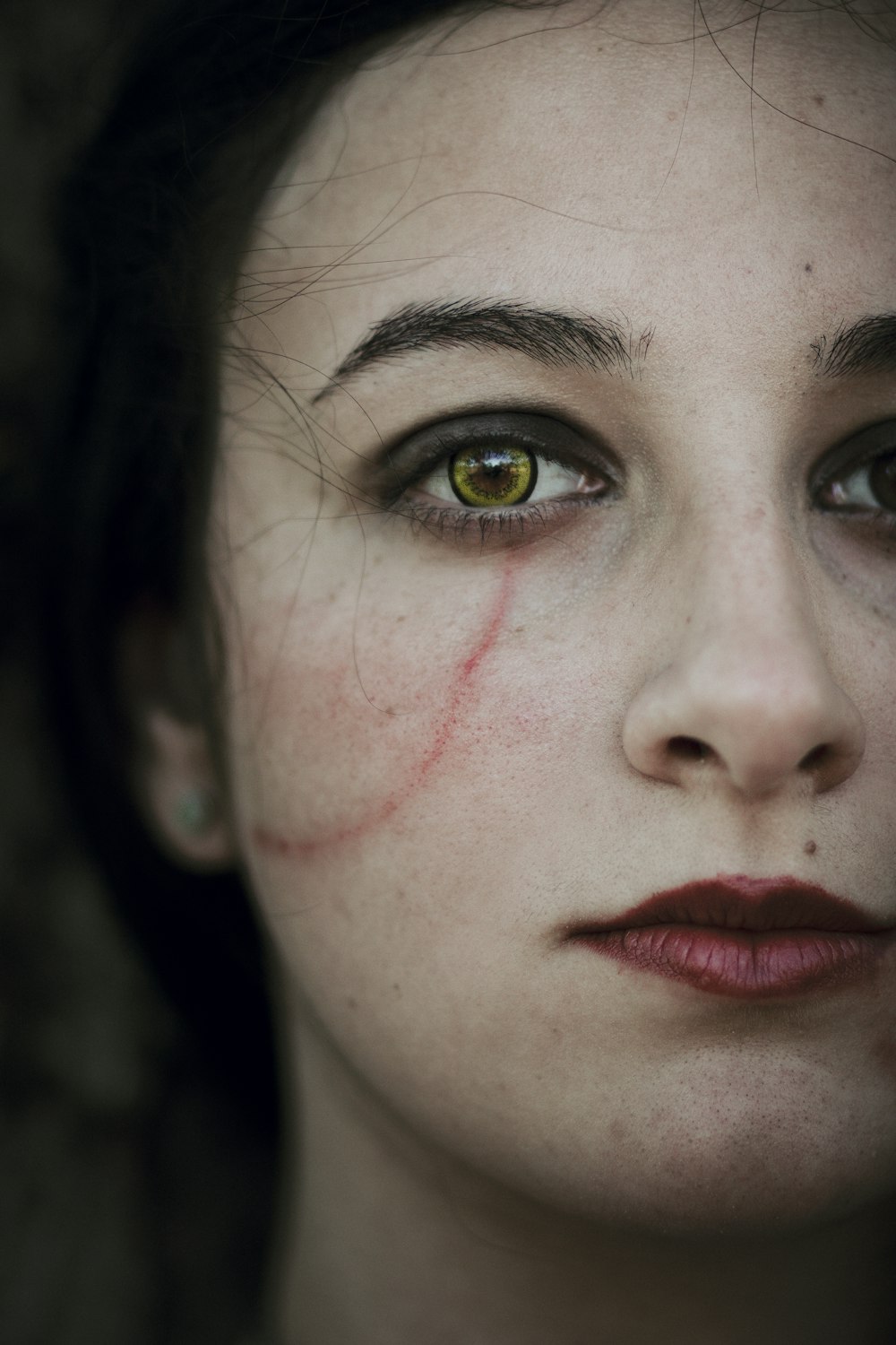 a close up of a woman's face with blood on her cheek