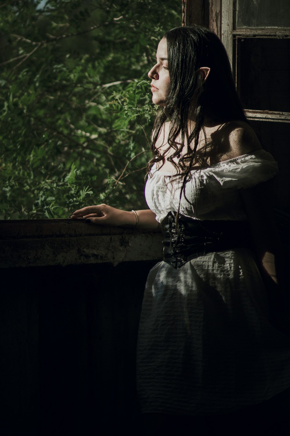 Una mujer con un vestido blanco mirando por una ventana