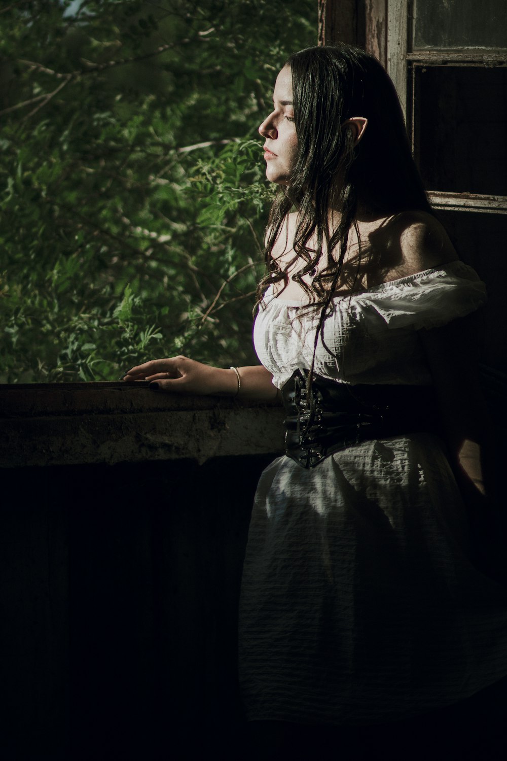 a woman in a white dress looking out a window