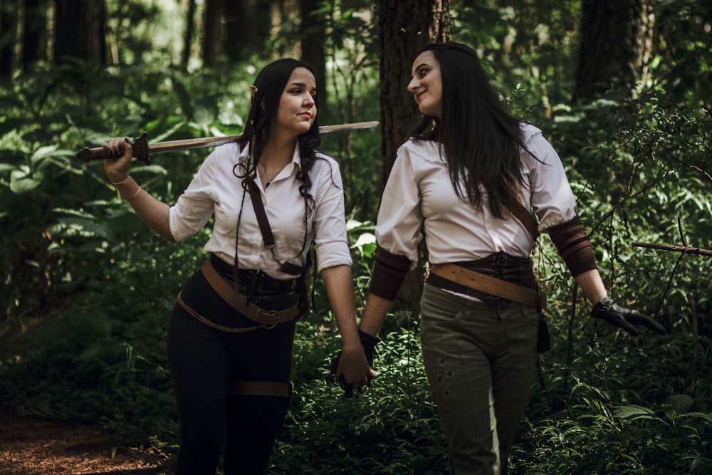 a couple of women standing next to each other in a forest