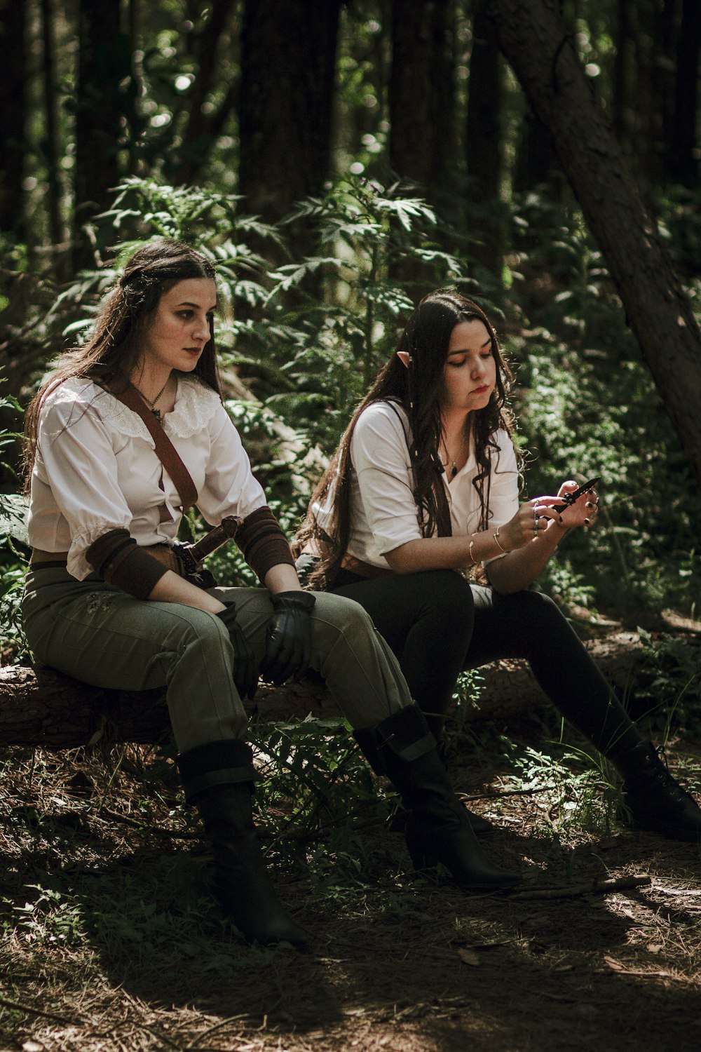 two women sitting on a log in the woods