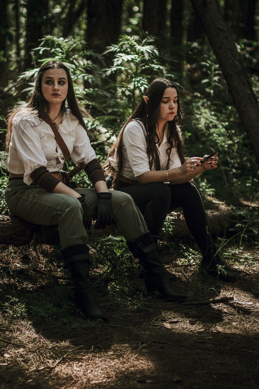 two women sitting on a log in the woods