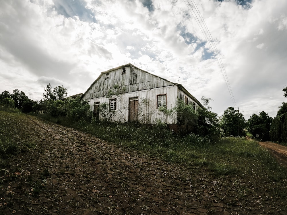 a run down barn sitting on top of a lush green field