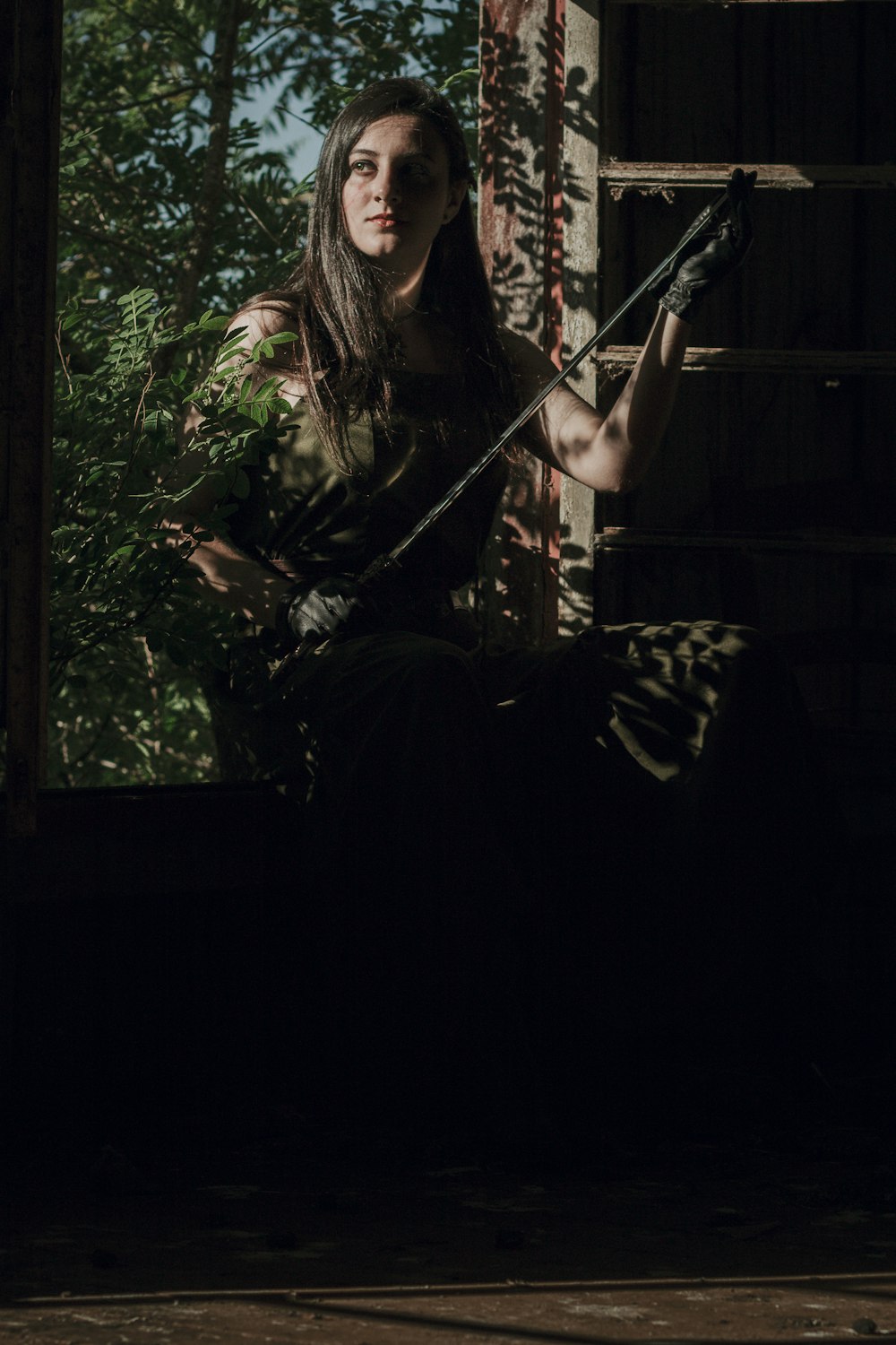 a woman sitting on a window sill holding a sword