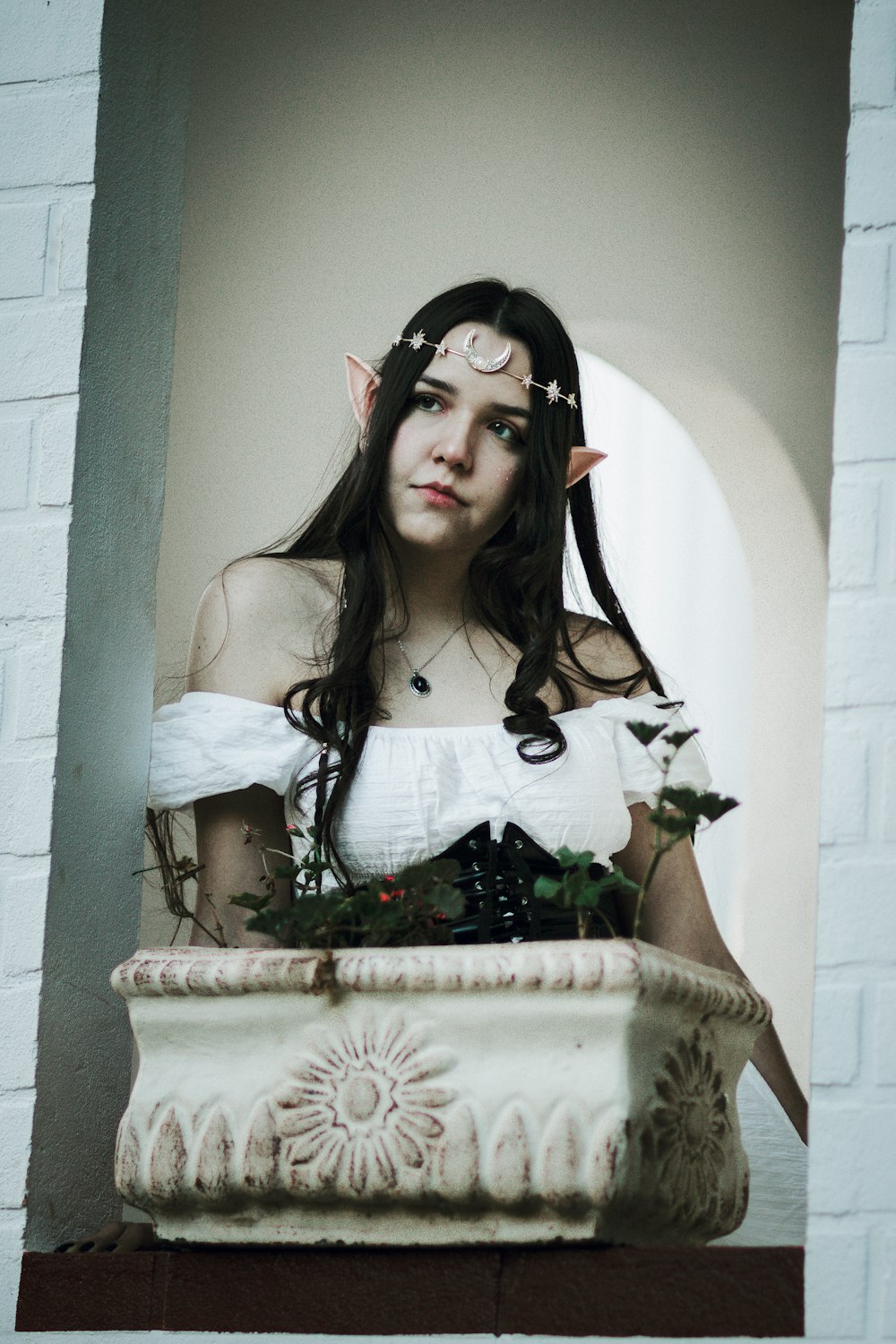 a woman in a white dress is holding a potted plant