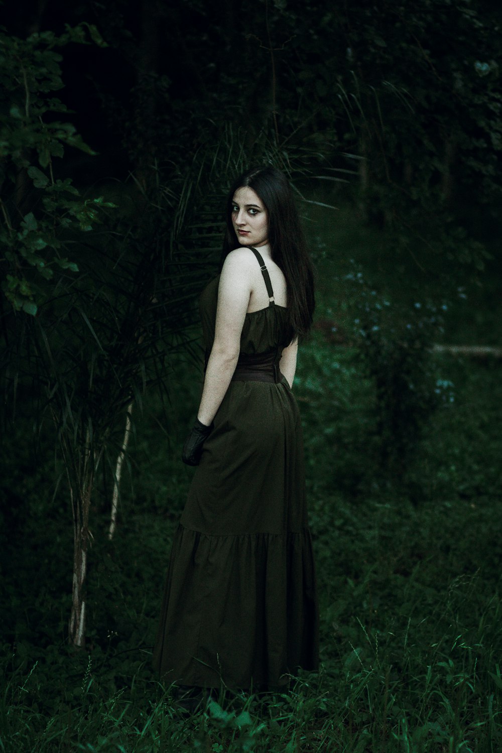 uma mulher em um vestido preto em pé em uma floresta