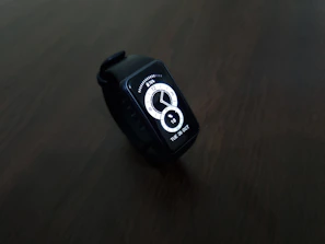 A stylish smart watch with a vibrant digital display showing health stats, set against a clean white background.