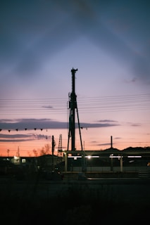 A towering oil drilling rig silhouetted against a vibrant sunset sky, highlighting the intricate machinery.