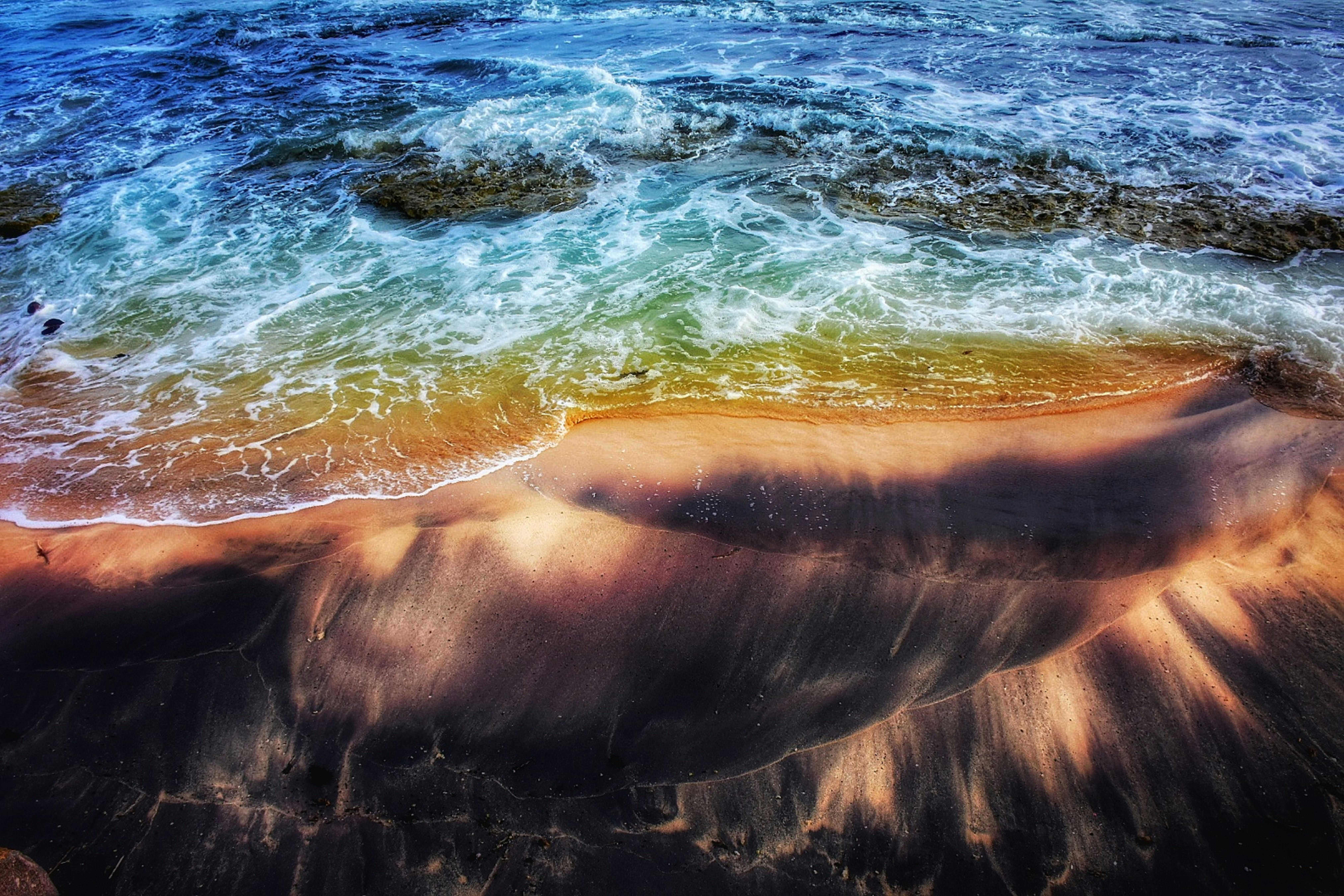 an aerial view of a beach with waves coming in