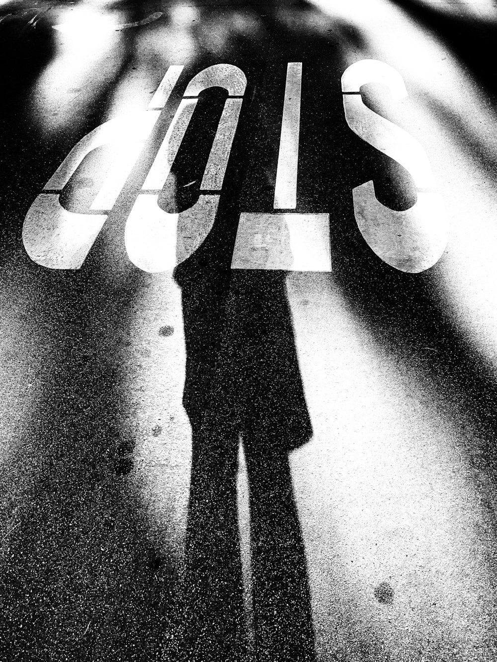 a shadow of a person standing next to a stop sign