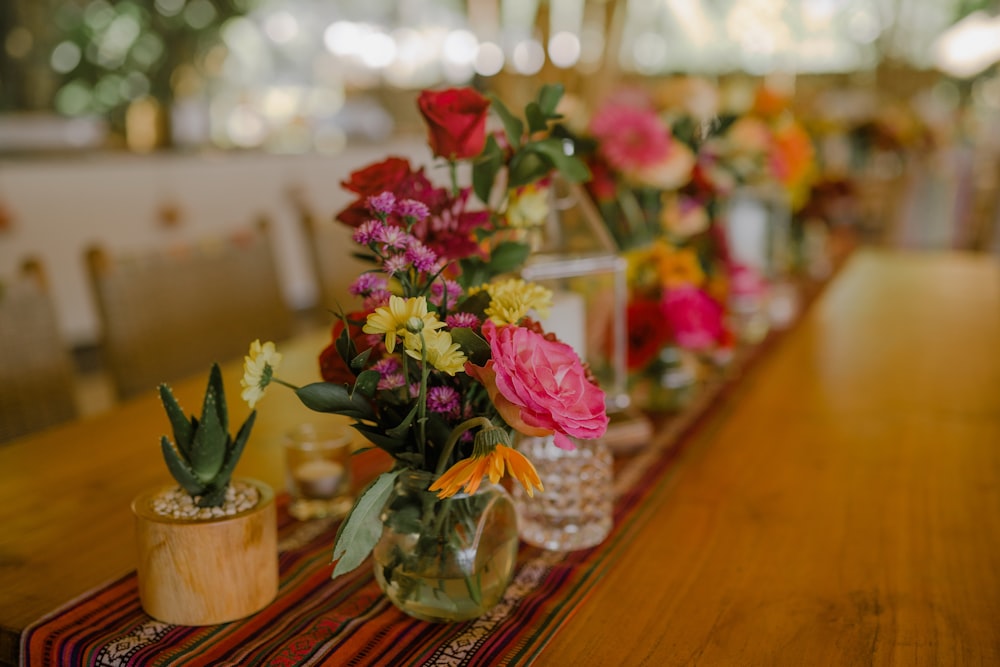 a wooden table topped with vases filled with flowers