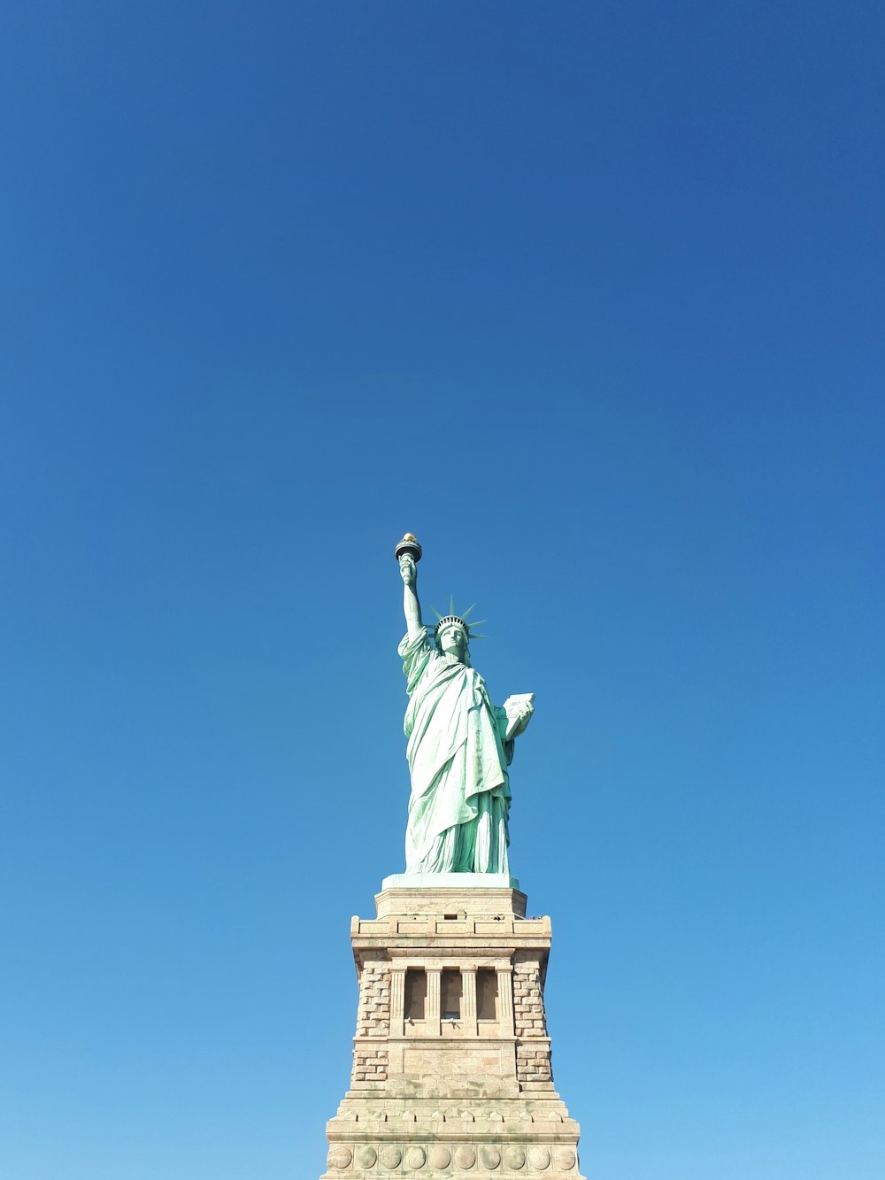 the statue of liberty stands tall against a blue sky