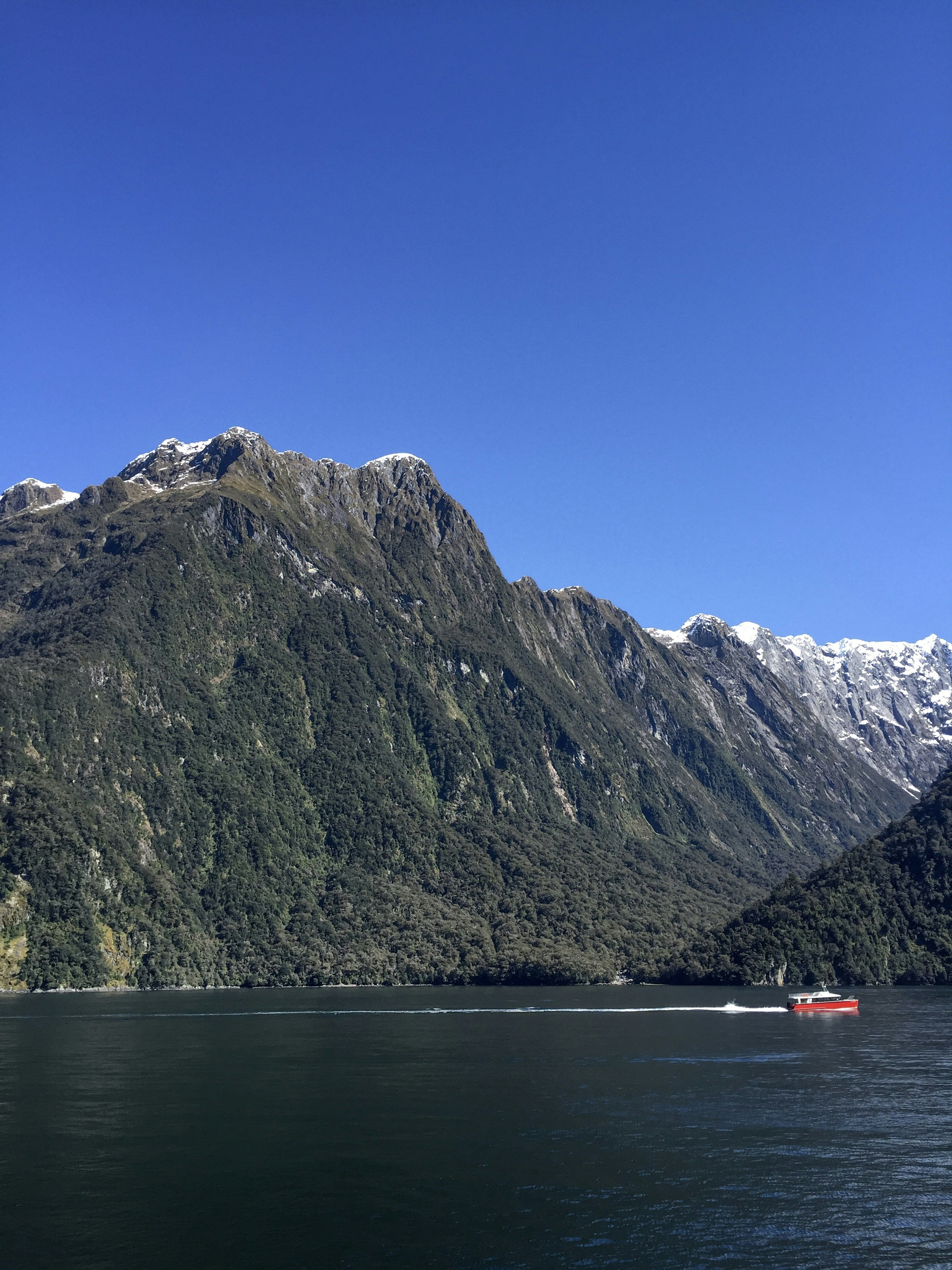 a boat is on the water in front of a mountain range