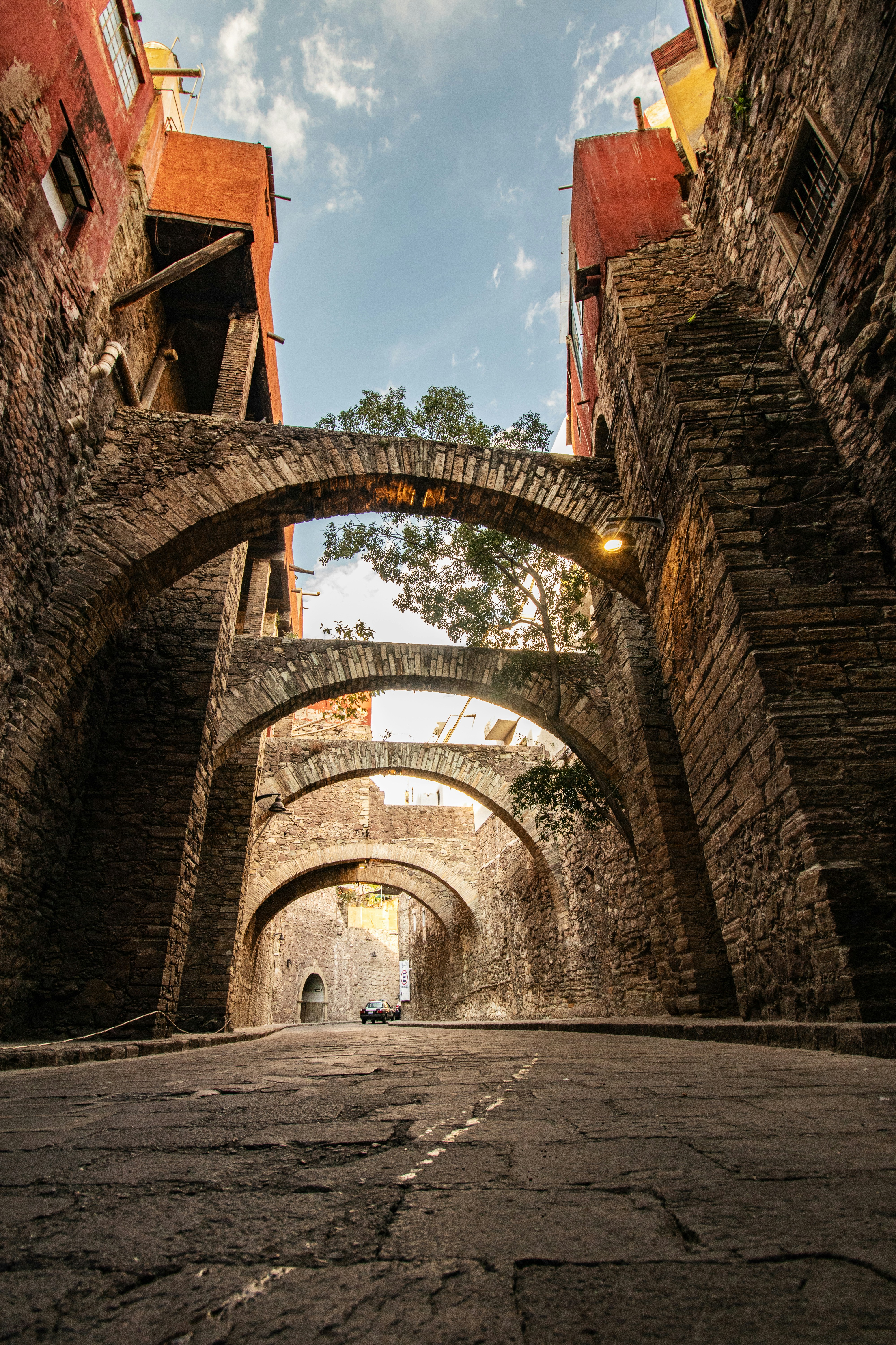 Un callejón estrecho con un arco de piedra y edificios de ladrillo