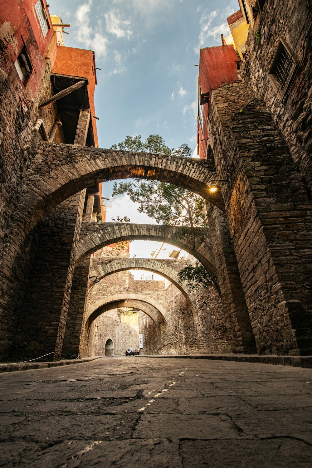 a narrow alleyway with a stone arch and brick buildings