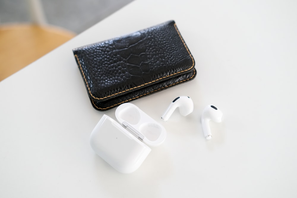 a pair of ear buds sitting next to a wallet