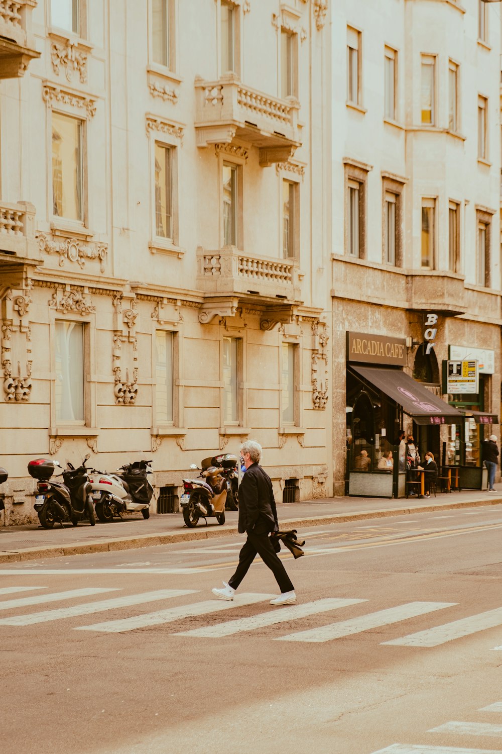 a man walking across a street next to a tall building