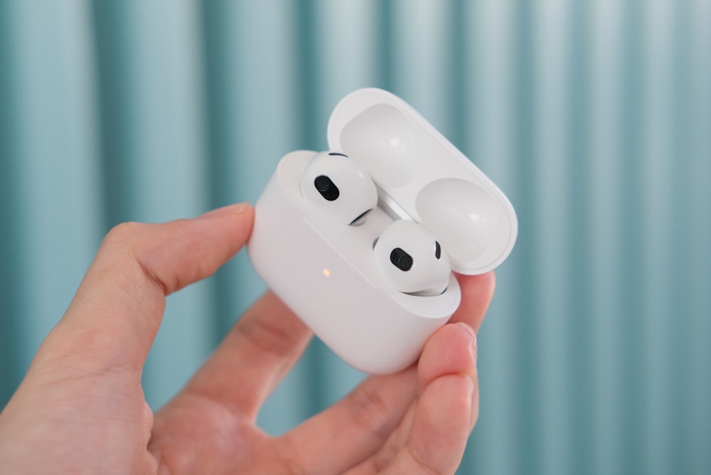 a person holding a pair of airpods in their hand